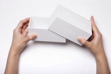 Beyaz masada beyaz bir kutu tutan bir kadın.