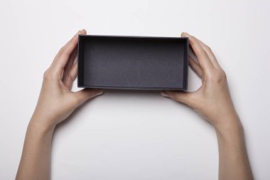 Kadın eli beyaz masada siyah bir kutu tutuyor.