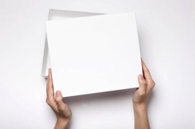 Beyaz masada beyaz bir kutu tutan bir kadın.