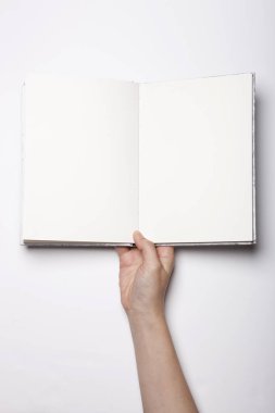 Beyaz masaya yayılmış boş bir kitabı tutan kadın.