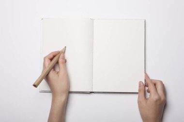 Beyaz masaya yayılmış boş bir kitabı tutan kadın.