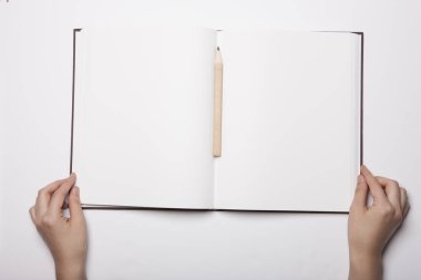 Beyaz masaya yayılmış boş bir kitabı tutan kadın.