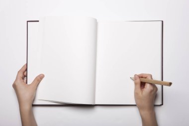 Beyaz masaya yayılmış boş bir kitabı tutan kadın.