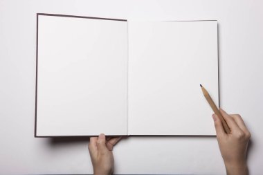 Beyaz masaya yayılmış boş bir kitabı tutan kadın.