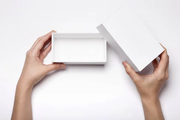 Frauenhand Hält Eine Weiße Schachtel Auf Dem Weißen Tisch — Stockfoto
