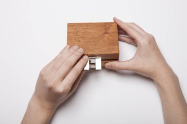 Bir kadın beyaz masada tahta bir kutu tutuyor..