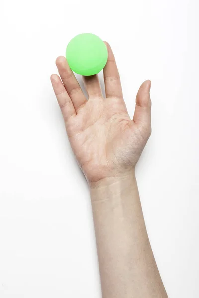 Mão Mulher Segurar Uma Bola Borracha Verde Mesa Branca — Fotografia de Stock