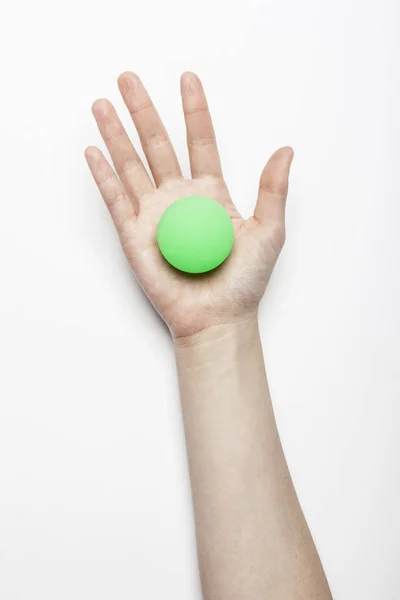 Mão Mulher Segurar Uma Bola Borracha Verde Mesa Branca — Fotografia de Stock