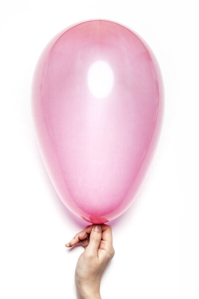 Woman hand hold a pink balloon on the white table.