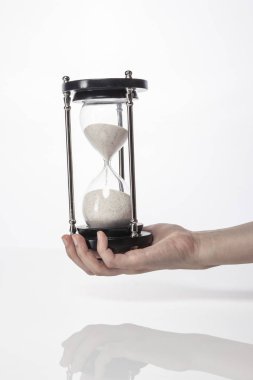 Kadın (kadın) bir vintage kum zamanlayıcı izole beyaz el ele.