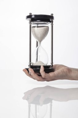 Kadın (kadın) bir vintage kum zamanlayıcı izole beyaz el ele.