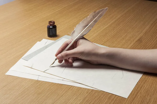 woman hand hold a pen with letter on the wood table.