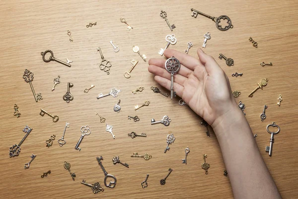 hand hold a many small keys on the wood table.