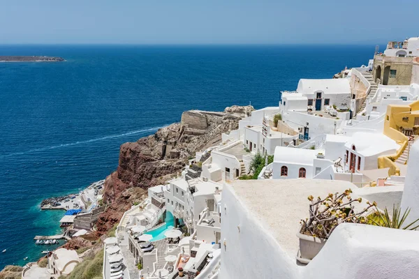 Küçük küçük beyaz evler, oteller, kafeler ve havuzları ve Santorini, Yunanistan, Oia köyünde küçük kiliseler. Limana görüntülemek.