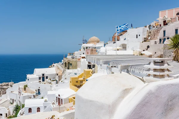 Tiny little white houses, hotels with cafes and pools and small churches in the Oia village at Santorini, Greece.