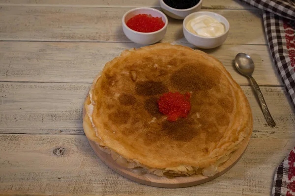 Pancakes with red caviar on a wooden texture — Stock Photo, Image