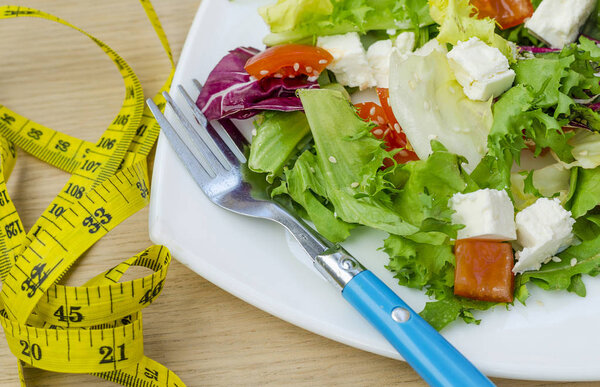 Диетический салат с помидорами и сыром фета на тарелке
