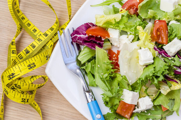 Диетический салат с помидорами и сыром фета на тарелке
