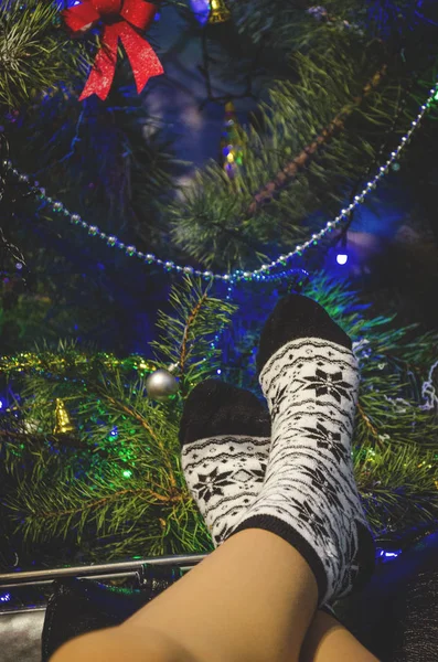 woman's legs in socks on the background of the Christmas tree