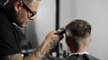 Tattoed berber kuaför dükkanında müşteri için saç kesimi hairclipper kullanarak yapar, saç kesimi ve tıraş Kuaför, berber dükkanı ve tıraş salon mans