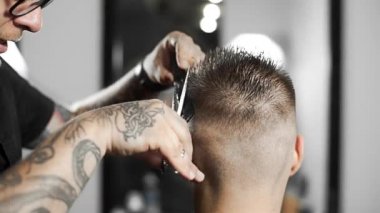 Tattoed berber kuaför dükkanında müşteri için saç kesimi makas ve tarak kullanarak yapar, saç kesimi ve tıraş Kuaför, berber dükkanı ve tıraş salon mans