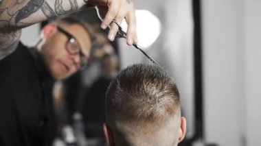 Tattoed berber kuaför dükkanında müşteri için saç kesimi makas ve tarak kullanarak yapar, saç kesimi ve tıraş Kuaför, berber dükkanı ve tıraş salon mans