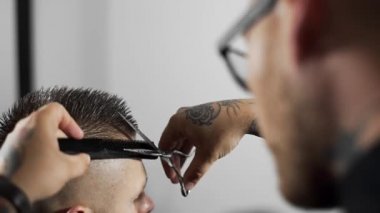 Tattoed berber kuaför dükkanında müşteri için saç kesimi makas ve tarak kullanarak yapar, saç kesimi ve tıraş Kuaför, berber dükkanı ve tıraş salon mans