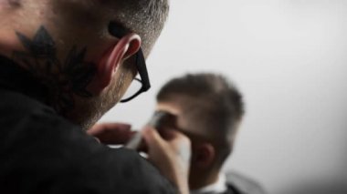 Tattoed berber kuaför dükkanında müşteri için saç kesimi hairclipper kullanarak yapar, saç kesimi ve tıraş Kuaför, berber dükkanı ve tıraş salon mans