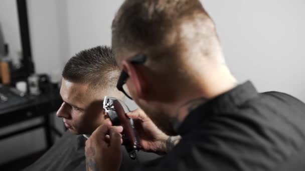 Tattoed Kapper kapsel voor klant bij de kapper maakt met behulp van hairclipper, mans kapsel en scheren bij de kapper, Kapper en scheren salon — Stockvideo