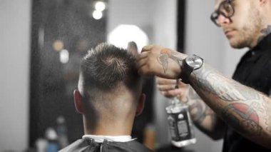 Kuaför saç spreyi tarafından ıslatıyor ve onları tarak, Kuaför Salonu, müşteride mans için saç kesimi ve tıraş Kuaför, berber dükkanı ve tıraş salon tattoed Kuaför saç kesimi yapar