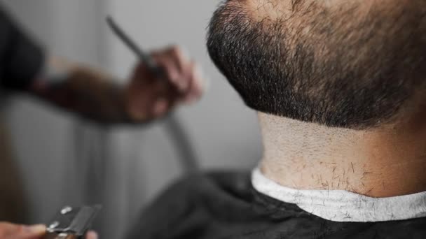 Barbeiro tatuado tosquia a barba dos clientes usando aparador na barbearia, corte de cabelo homem e barbear no cabeleireiro, barbearia e salão de barbear — Vídeo de Stock