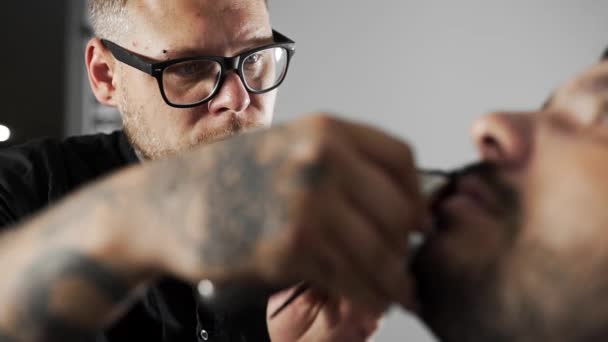 Татуйований перукар носить м'яз клієнтів, використовуючи тример і гребінець в перукарні, чоловічу зачіску і гоління в перукарні, перукарні і гоління салону — стокове відео