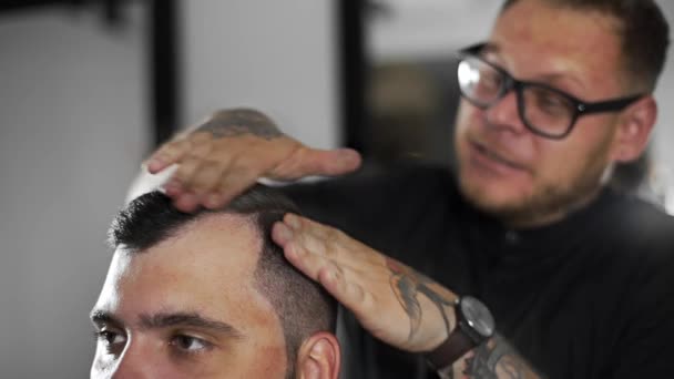 Peluquero tatuado hace peinado con gel de pelo para el cliente después de corte de pelo en la peluquería, corte de pelo mans y afeitado en la peluquería, peluquería y salón de afeitar — Vídeos de Stock