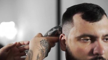 Tattoed berber kuaför dükkanında müşteri için saç kesimi hairclipper kullanarak yapar, saç kesimi ve tıraş Kuaför, berber dükkanı ve tıraş salon mans