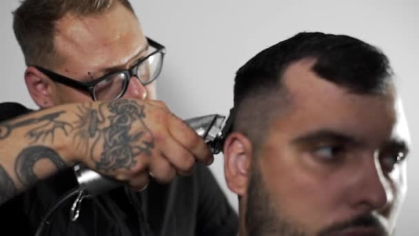Tattoed Kapper kapsel voor klant bij de kapper maakt met behulp van hairclipper, mans kapsel en scheren bij de kapper, Kapper en scheren salon — Stockvideo