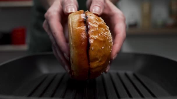 女性はファーストフード、焼きパン、健康に悪いレシピを料理、バーガーを作る熱いグリル鍋にパンを置く — ストック動画