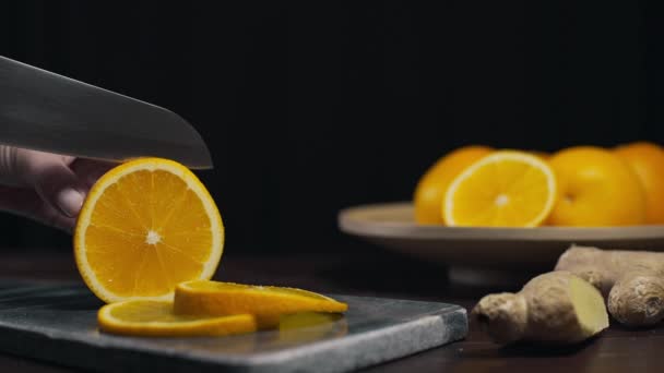 Orange wird mit scharfem Messer auf dem Steinbrett geschnitten, frische Orangenscheiben, Obst und Vitamine, vegetarische Ernährung, Herstellung von frischem Saft — Stockvideo