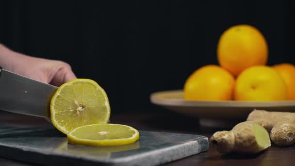 Limón en rodajas por cuchillo afilado en el tablero de roca, rodajas de naranja fresca, frutas y vitaminas, la dieta vegetariana, la fabricación de jugo fresco — Vídeos de Stock