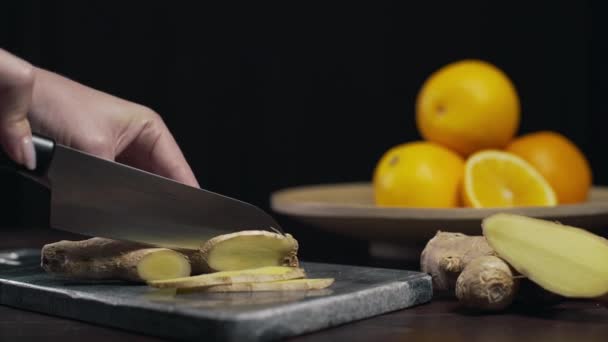 Ingwer wird mit scharfem Messer auf dem Steinbrett geschnitten, Scheiben frischer Ingwer, Gemüse und Vitamine, vegetarische Ernährung, Herstellung von Vitamingetränken gegen Krankheit — Stockvideo