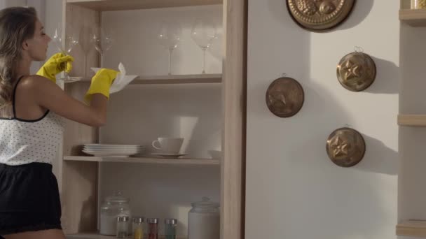 Sexig kvinna i gul gummi handskar avlägsnar damm prom hyllan i slow motion, ung kvinna städas huset, hushållssysslor — Stockvideo