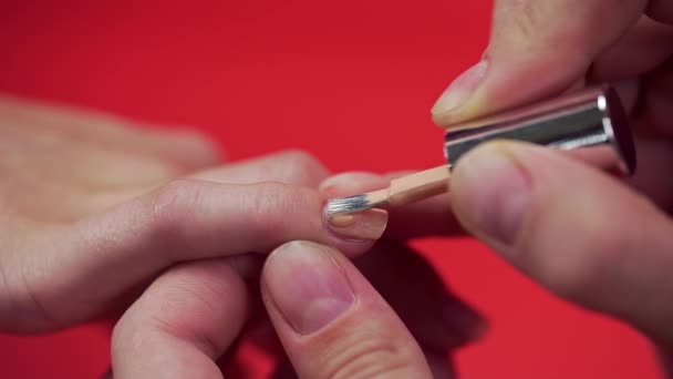 Манікюр фарбує клієнтів лаком для нігтів бежевого відтінку на червоному тлі, макіяжем та цвяхами, крупним планом наносить лак для нігтів — стокове відео