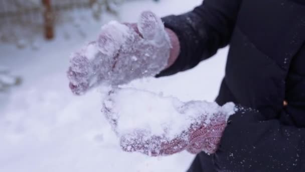Mujer en invierno guantes de punto hace bola de nieve y lo lanza, ropa de invierno, nieve en cámara lenta, juegos de invierno y diversión — Vídeos de Stock