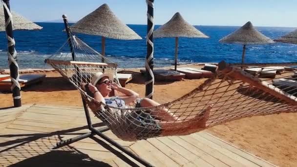 Mulher calafrios na rede na praia, férias no mar, relaxar na praia, mar e recreação, areia e água azul — Vídeo de Stock