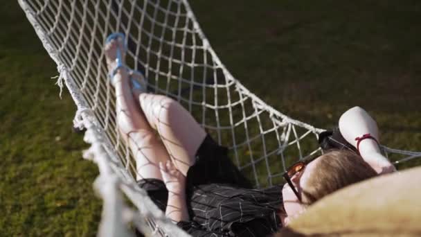 Mujer escalofríos en la hamaca al atardecer, vacaciones y relax, naturaleza y recreación — Vídeos de Stock