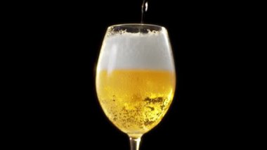 Altın köpüklü bira bardağı bira cam dökülür yavaş yavaş arka planda karanlık, kabarcıklar bira, bira ışık