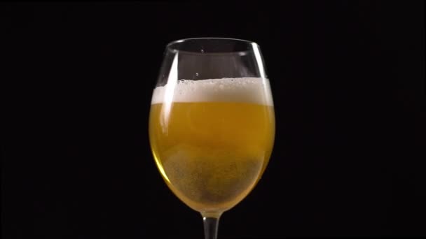 La cerveza espumosa dorada se vierte lentamente en el vaso, el vaso de cerveza en fondo oscuro, las burbujas en la cerveza, la cerveza ligera — Vídeo de stock