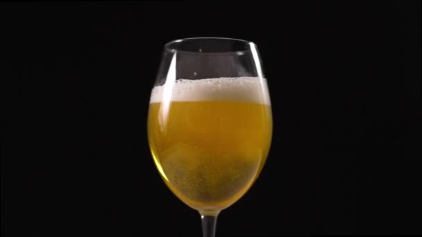 Golden birra schiumosa viene versato al bicchiere al rallentatore, bicchiere di birra in background scuro, bollicine di birra, birra leggera, fullhd 60fps — Video Stock
