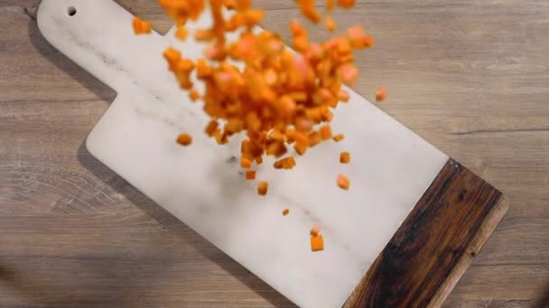 Gehackte Karotte fällt in Zeitlupe auf das Steinbrett auf dem Tisch, fallendes Gemüse, Nahrung in Superzeitlupe, Tischplatte oben 240fps full hd — Stockvideo