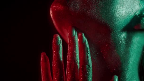 Ritratto di moda di donna che si tocca il collo con la punta delle dita in brillantini e luci al neon in stile anni '80, video ritratto con neon misto verde e rosso su sfondo scuro, girato su proporzioni blackmagic 422 — Video Stock