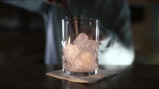 Cantinero vierte whisky al jigger y luego al vaso con hielo, haciendo de bebida alcohólica, cóctel en el bar, cantinero en el trabajo, 4k UHD 60p Prores HQ 422 — Vídeo de stock